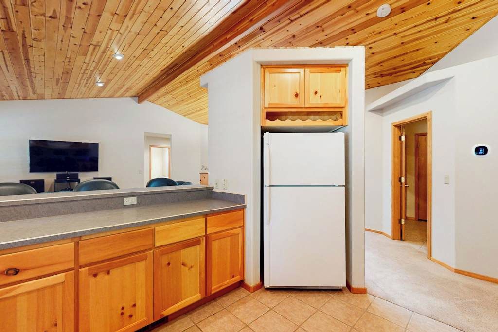 A kitchen with wooden cabinets, a white refrigerator, and a built-in oven.
