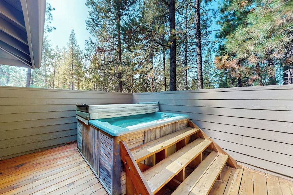 Een hottub op een houten terras, met uitzicht op een bos.