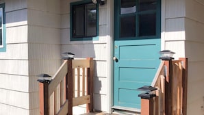 A house with a teal door, a window with a light fixture, and a wooden staircase. - Dog-friendly home with two full kitchens & a gas grill - walk to the ocean (Reedsport)