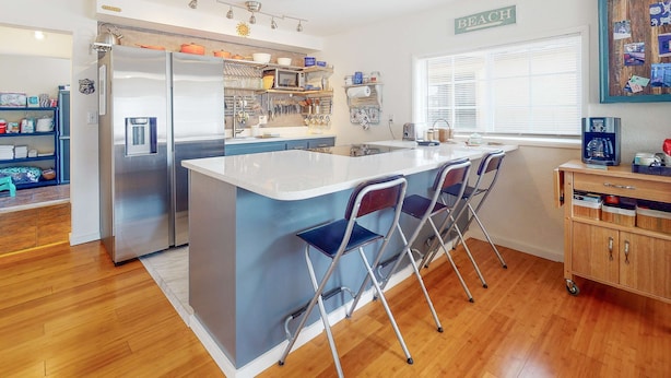 A modern kitchen with a central island, bar stools, a refrigerator, and a coffee machine. - Dog-friendly home with two full kitchens & a gas grill - walk to the ocean (Reedsport)
