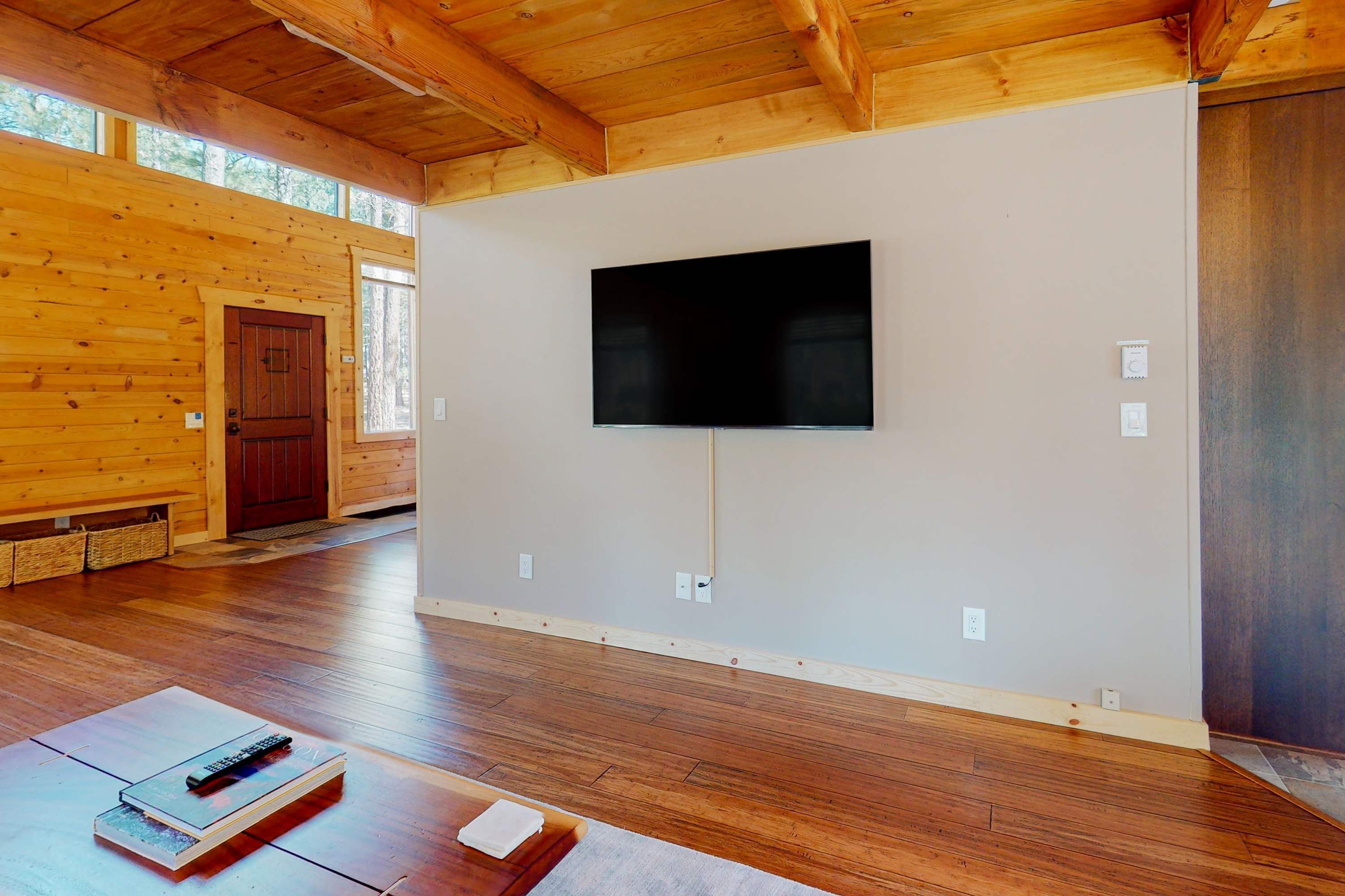A room with a wooden floor, a mounted television, and a door.