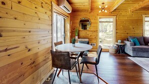 Ein Holzblock-Interieur mit Esstisch, Stühlen, einer Couch und einem Deckenventilator.