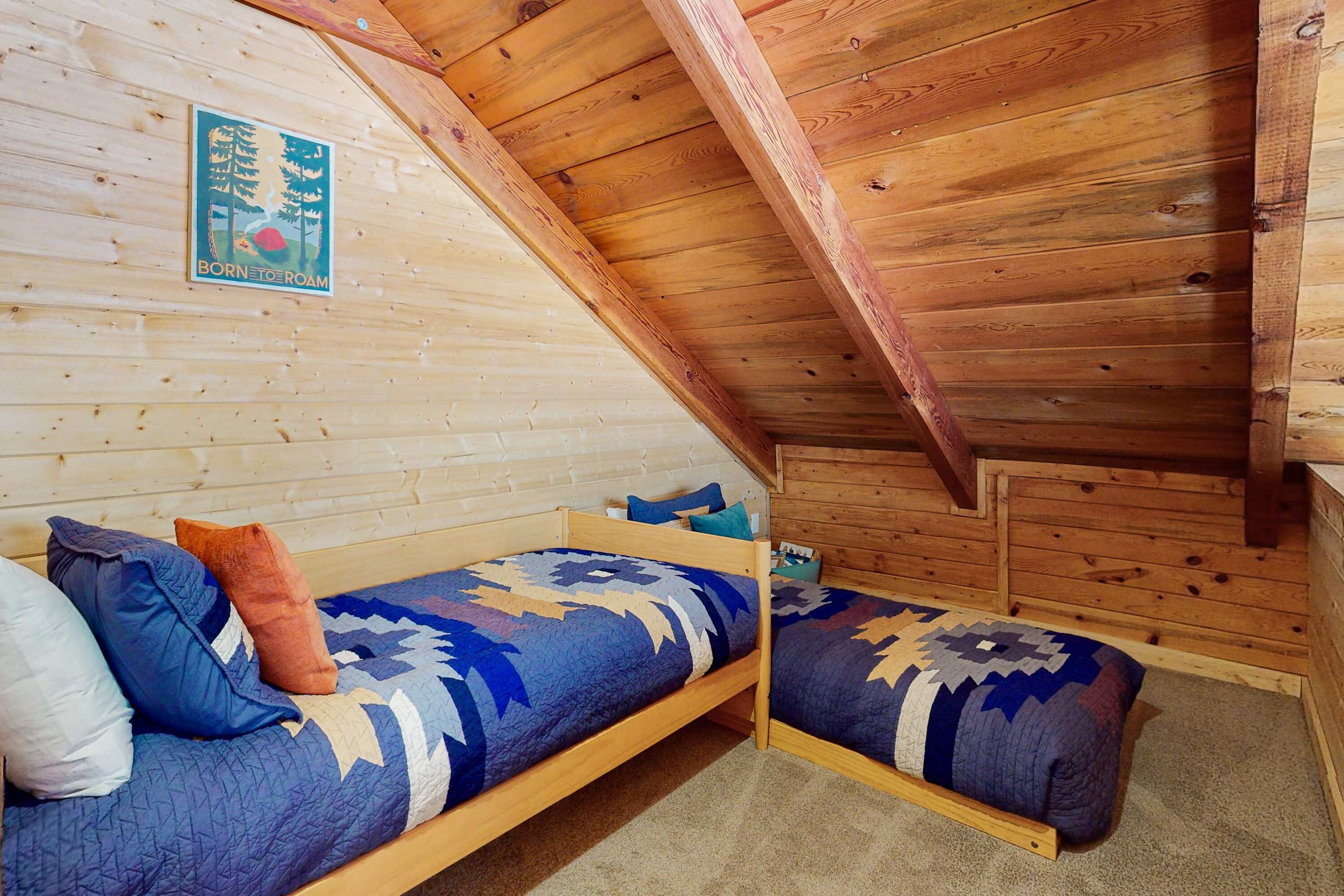 Una baita in legno con un letto a soppalco e un letto a castello, entrambi con biancheria da letto fantasia.
