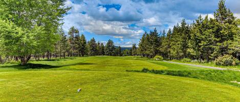 A golf course with a clear sky, surrounded by trees.