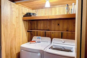Ein Waschbereich mit zwei Waschmaschinen, Holzwänden und einem Regal mit Reinigungsmitteln.