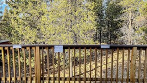 A wooden fence with signs, likely indicating a park or natural area. - Charming 2-story chalet with deck, wood stove, Deschutes River access (Sunriver)