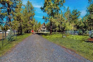 Une allée de gravier mène à une maison entourée d’arbres.