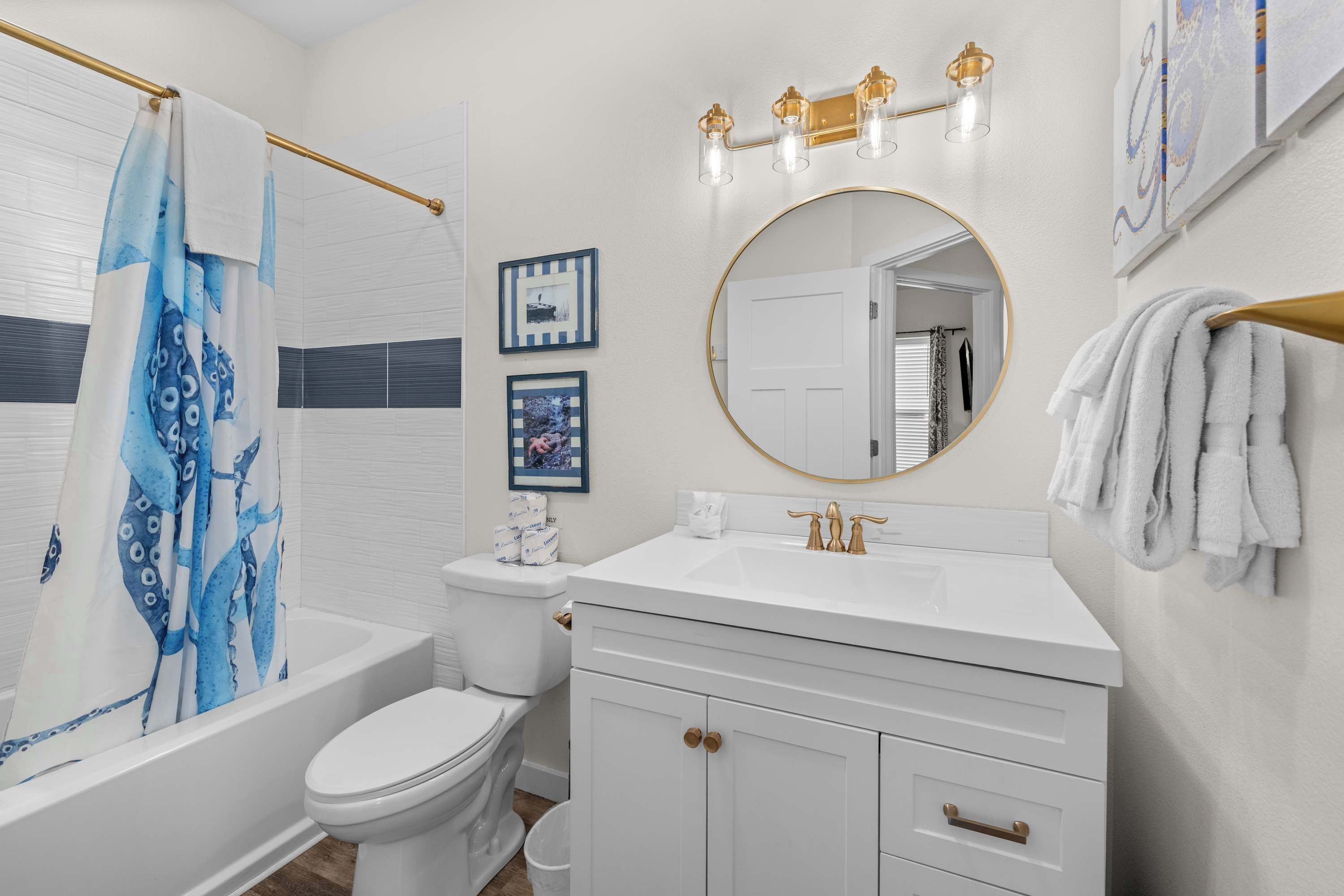 A bathroom with a bathtub, toilet, vanity, and a mirror.