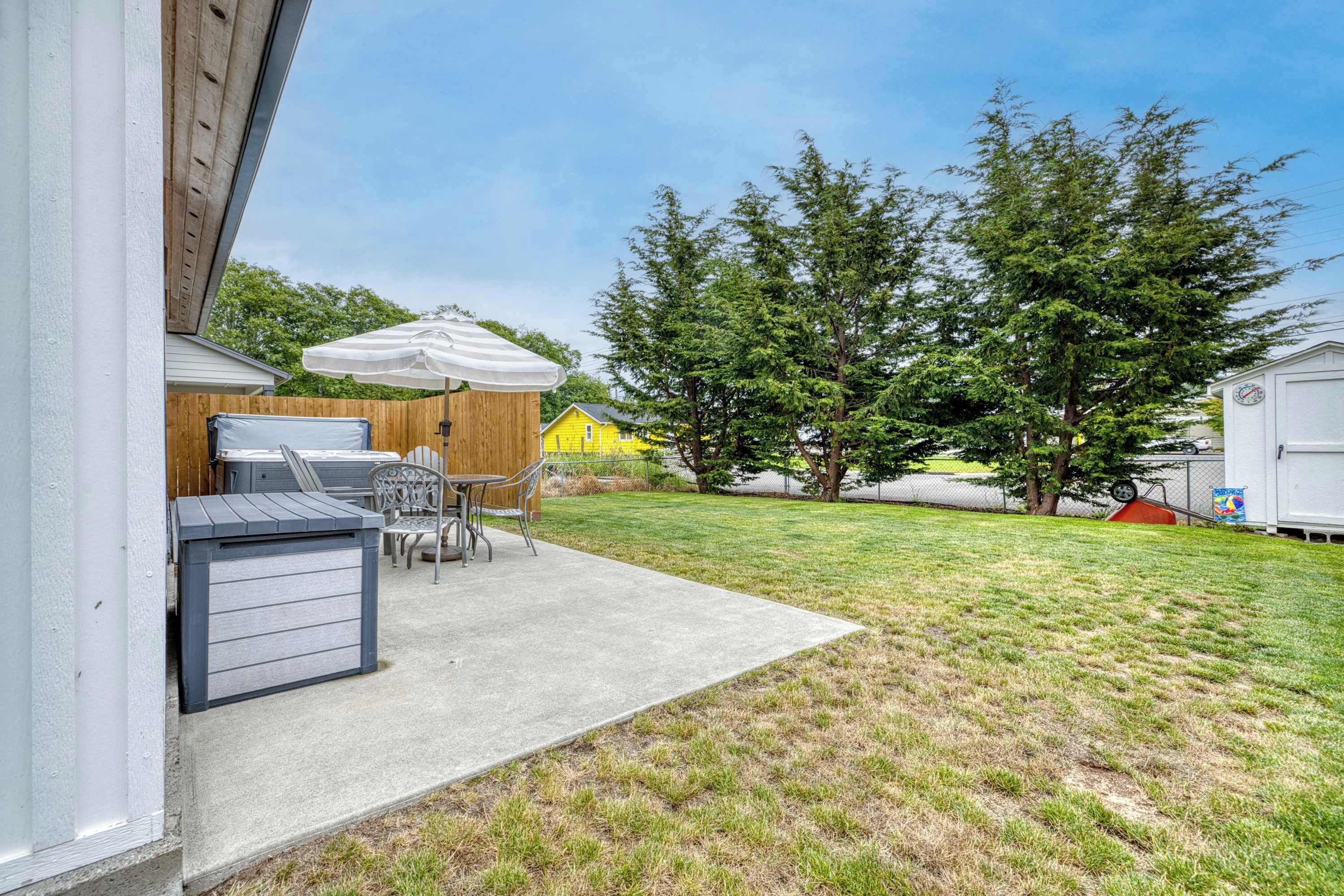 A patio area with a table and chairs, a covered seating area, and a grassy lawn.
