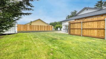 Ein wohnlicher Garten mit gepflegtem Rasen, Holzzaun und Garage mit Metalltor.