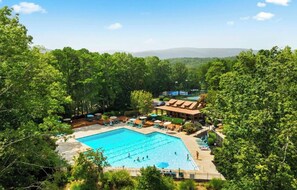 A swimming pool surrounded by lush greenery, with a building in the background. - Lake Arrowhead Retreat w/ Hot Tub, Fire Pit, Game Room and Lake Access, Near ATL (Waleska)