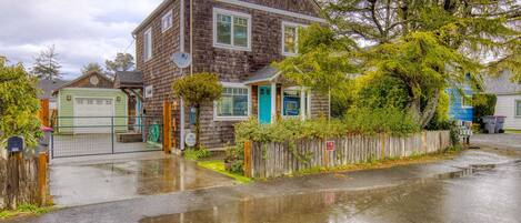 A two-story house with a garage, a front porch, and a wooden fence.