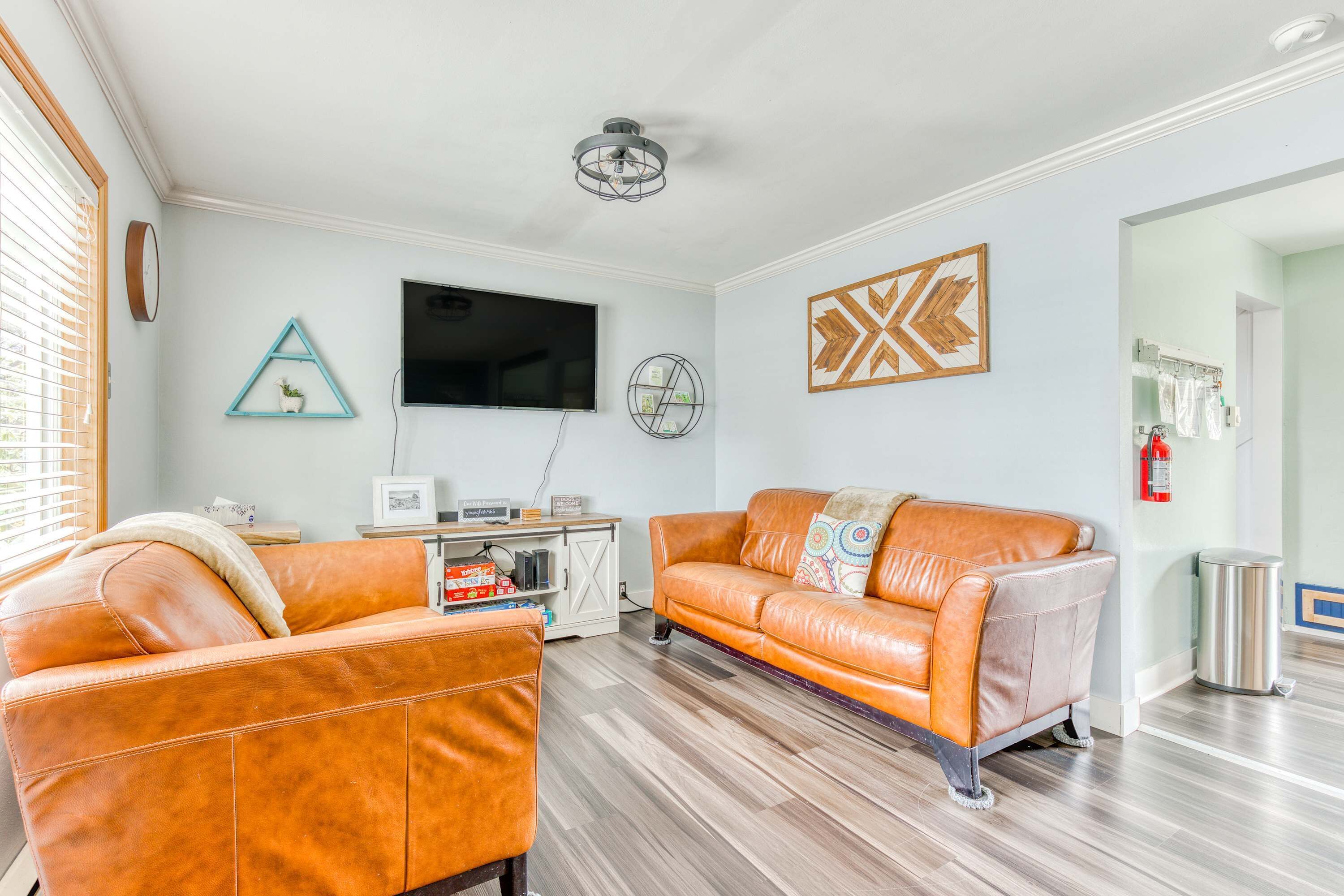 A living room with two leather sofas, a flat-screen TV, a ceiling fan, and artwork on the walls.