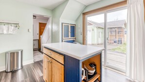 Eine Küche mit Arbeitsplatte, Schränken und einem Mülleimer. Eine Tür führt zu einem Balkon.