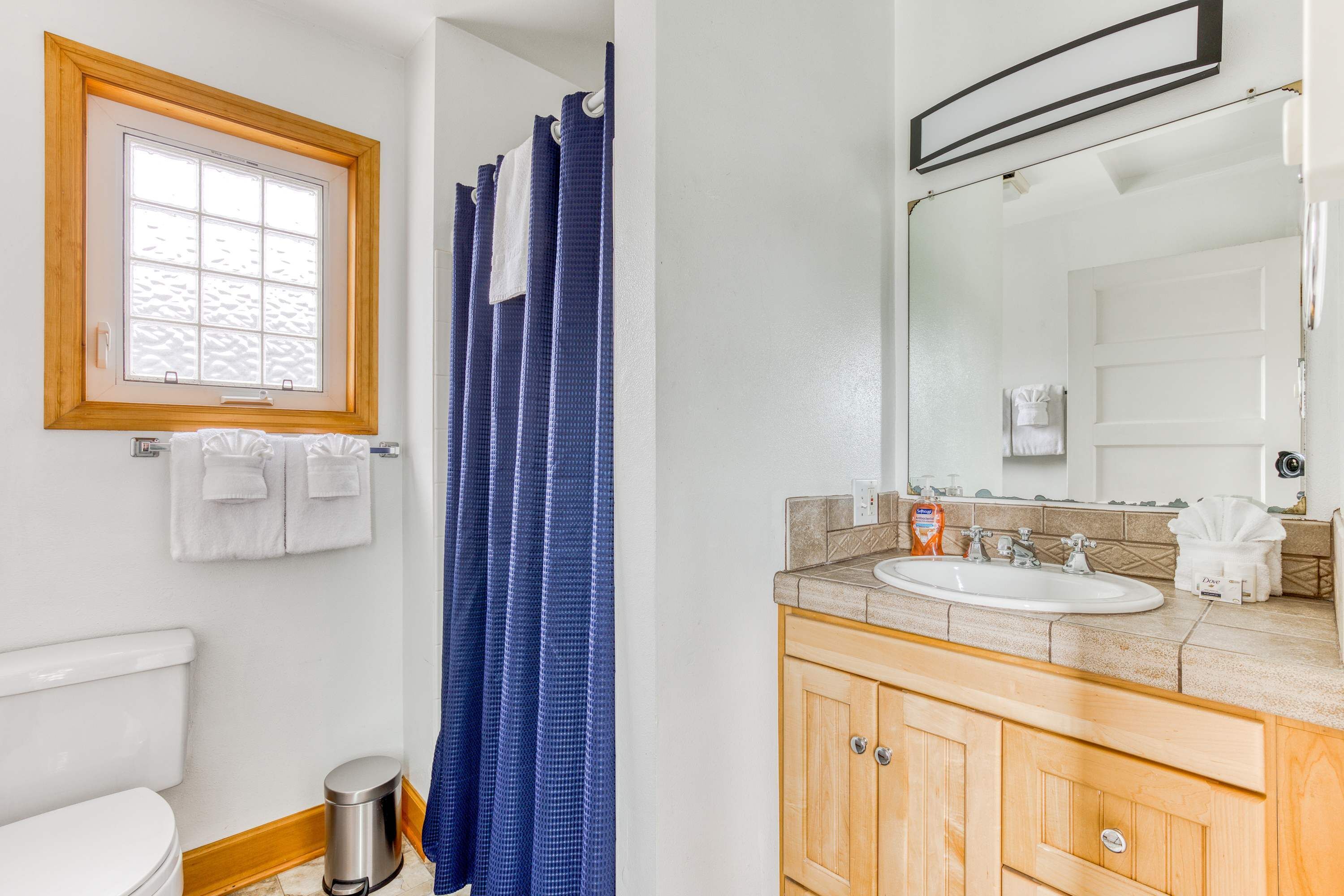 A bathroom with a toilet, a sink, a mirror, and a shower curtain.