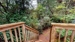 A wooden staircase leading into a forested area with railings on both sides. - Dog-Friendly Home with Expansive Deck with Hot Tub and Dock on Woahink Lake (Florence)