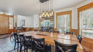 A dining area with a long wooden table, black chairs, and hanging light fixtures. - Lodge-style luxury in Sunriver - hot tub, fireplace, gas grill, games (Sunriver)