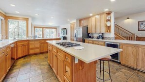 A spacious kitchen with wooden cabinets, a central island, and a built-in oven. - Lodge-style luxury in Sunriver - hot tub, fireplace, gas grill, games (Sunriver)