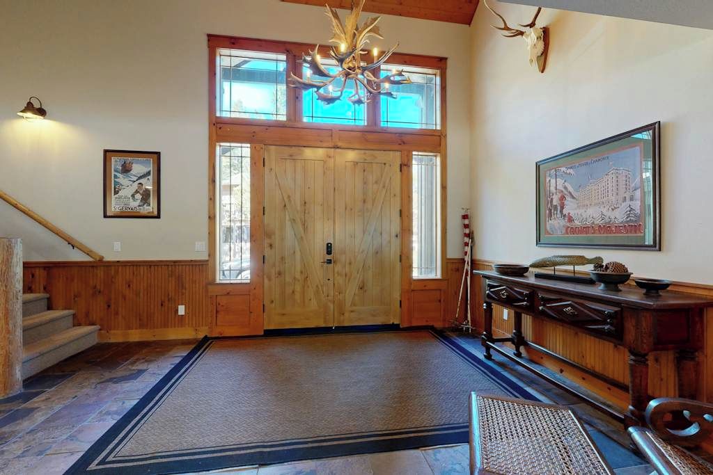 A wooden interior with a large double door, a chandelier, and a mounted animal skull.