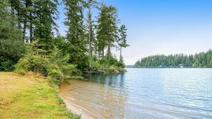 A lakeside view with a dock, dense trees, and a clear sky.