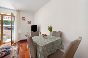 A dining area with a table, chairs, a vase with flowers, a bowl of fruit, and a television on the wall. - Apartment Residence Leonardo with Mountain View, Central Location, Air Conditioning (Merano)