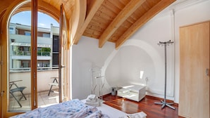 Un dormitorio con una cama grande, techo de madera, balcón y baño moderno.