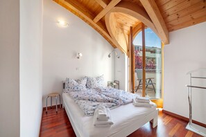 A bedroom with a bed, a stool, a glass door leading outside, and a wooden ceiling. - Apartment Residence Leonardo with Mountain View, Central Location, Air Conditioning (Merano)