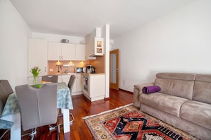 Un espai habitable compacte amb petita cuina, zona de menjador i sofà.