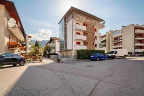 Ein mehrstöckiges Wohngebäude mit Balkonen, einem Parkplatz und blauem Himmel.