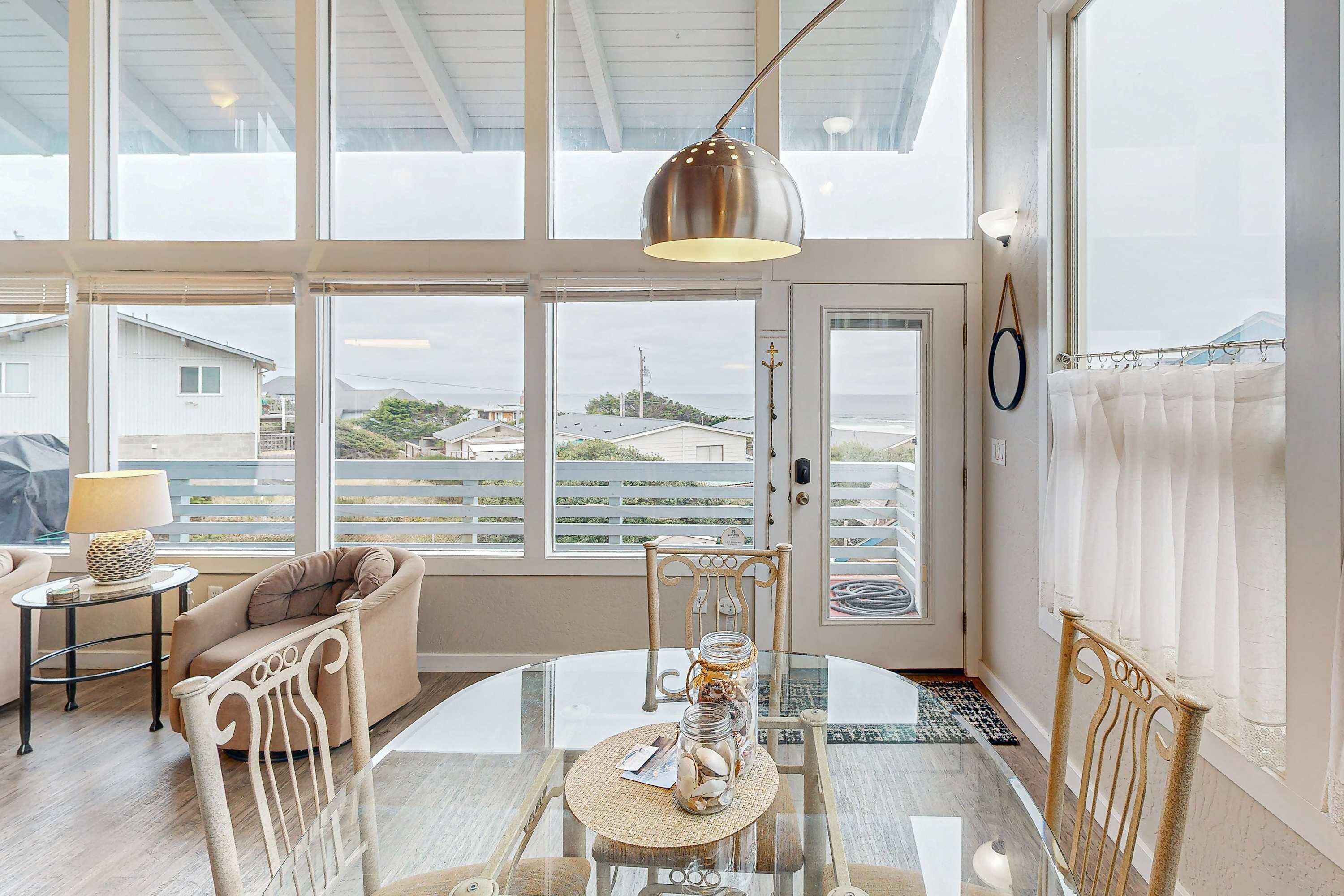 A room with a glass table, a chair, a lamp, a window with a view, and a ceiling light.