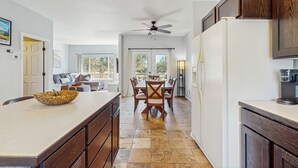 A kitchen with a dining area, a ceiling fan, and a coffee maker.