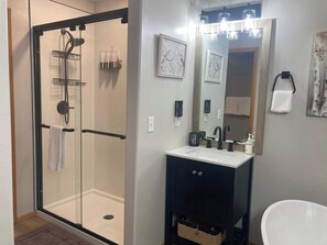 A bathroom with a glass-enclosed shower, a sink with a mirror, and a towel rack.