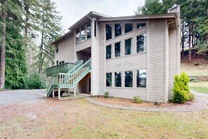 A two-story house with a green staircase, large windows, and a driveway.