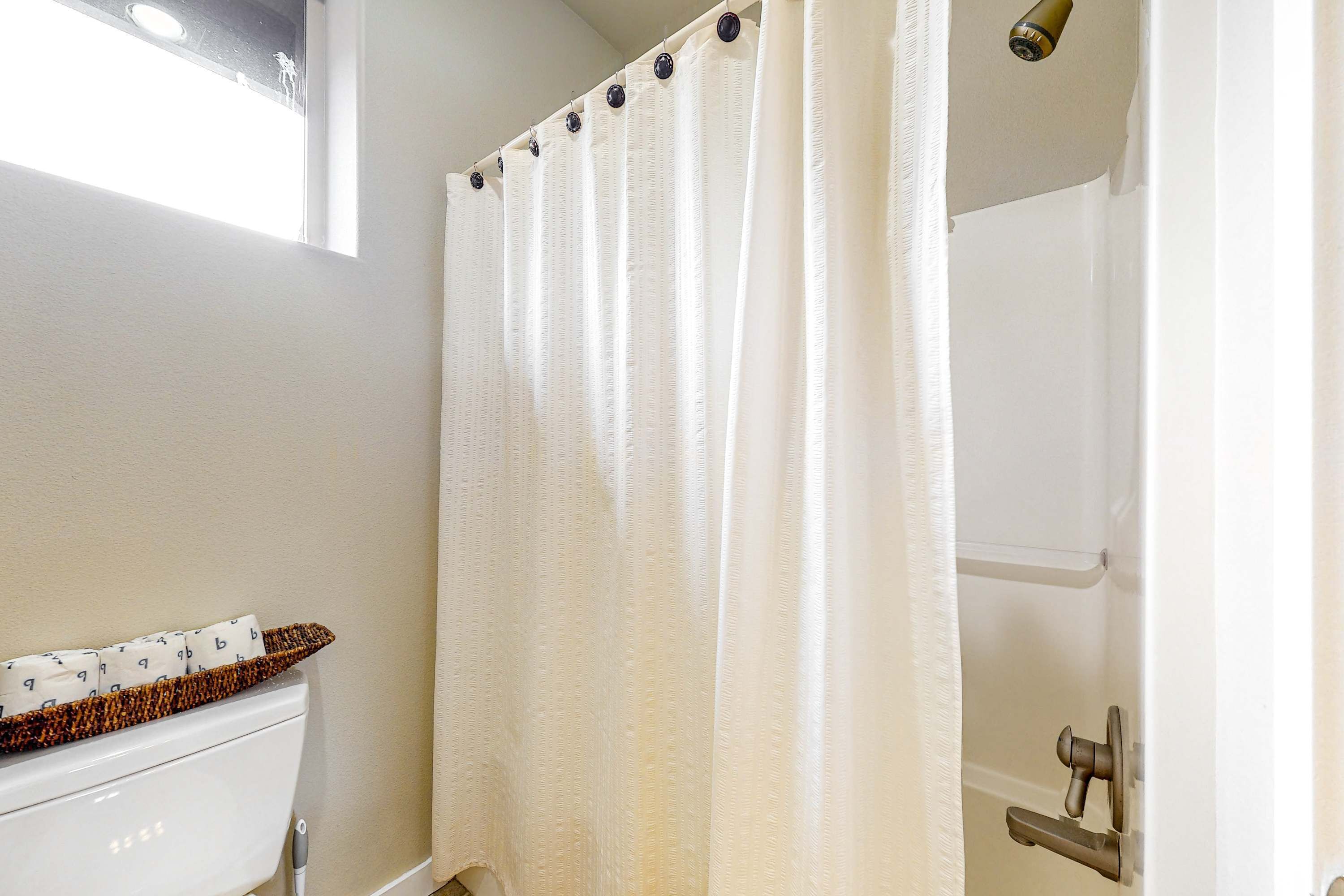 Ein Badezimmer mit weißer Duschvorhang, Toilette und einem Handtuchhalter mit gemusterten Handtüchern.