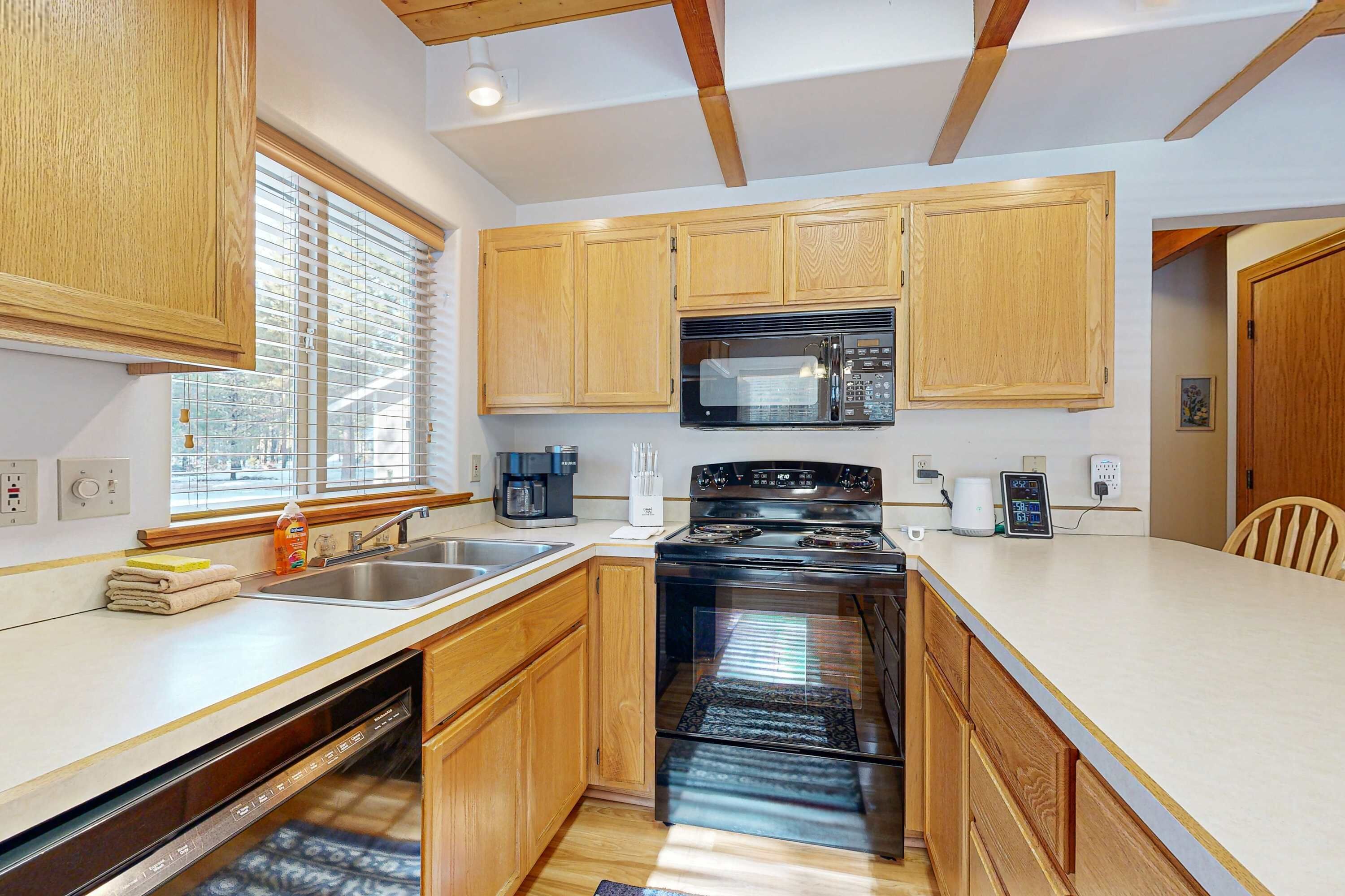 A modern kitchen with wooden cabinets, a built-in microwave, a stove, and a dishwasher.