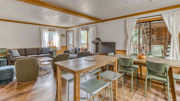 Un vaste espace de vie comprenant une table à manger en bois, des chaises vertes, un canapé et une cheminée.
