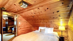 A wooden-paneled room with a bed, a nightstand, and a lamp. - Cozy, comfortable cottage in Government Camp (Government Camp)