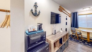 Une chambre équipée d’un four à micro-ondes, d’une machine à café, d’un téléviseur à écran plat, de meubles en bois et décorée sur le thème de la marine.