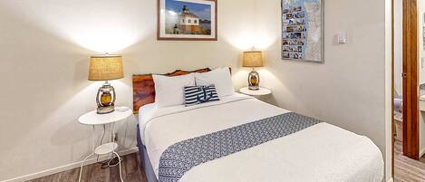 A neatly arranged hotel room with a bed, two bedside lamps, a framed picture on the wall, and a small table with a lamp.