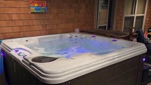 A hot tub with purple LED lights, a wooden wall, and a door in the background.