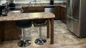 A modern kitchen with wooden cabinets, a stainless steel refrigerator, and a granite countertop.