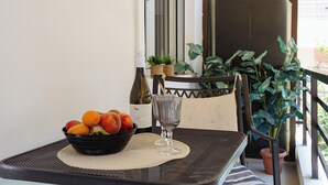 Ein Tisch mit einer Obstschale, einer Weinflasche und einem Glas auf einer gewebten Tischunterlage.