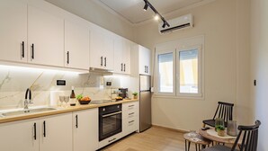 Eine moderne Küche mit weißen Schränken, einem Einbauofen und einem Essbereich mit rundem Tisch und Stühlen.