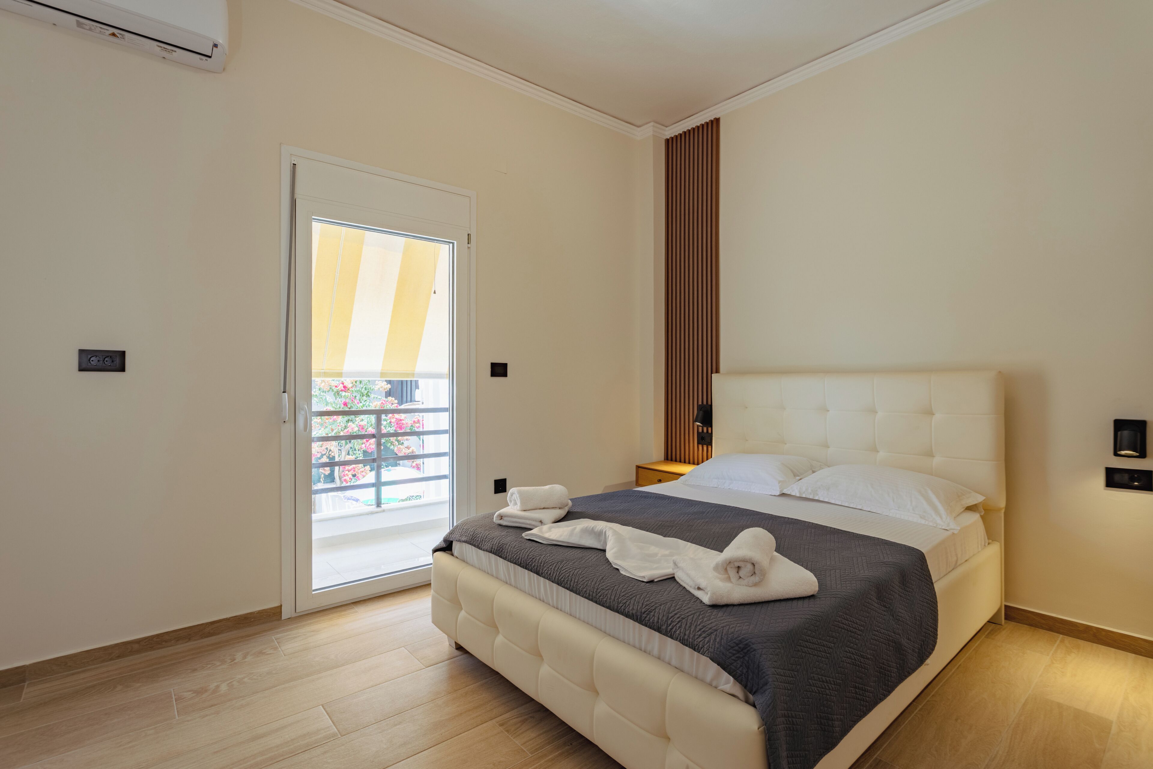 A bedroom with a bed, a door, a light switch, and a wall-mounted air conditioner.