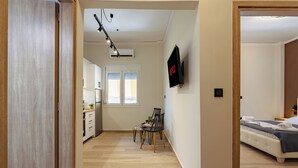 Ein modernes Hotelzimmer mit Bett, Nachttisch und einem an der Wand befestigten Fernseher.