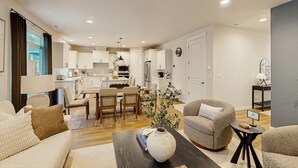 A modern living room with a sofa, armchair, coffee table, and a dining area with chairs and a table. - Spacious family friendly home with full kitchen, enclosed yard, washer & dryer (Eugene)