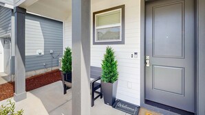 A front porch with a dark gray door, a small window, and a welcome mat. - Spacious family friendly home with full kitchen, enclosed yard, washer & dryer (Eugene)
