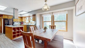 Una cocina moderna con armarios de madera, una isla central y un comedor con mesa y sillas.