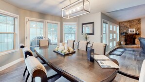 A spacious conference room with a long table, chairs, a chandelier, and a stone fireplace. - Spacious home with private hot tub, Ping-Pong (Sunriver)