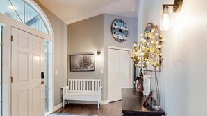 A hallway with a white bench, a clock, and a vase with flowers. - Spacious home with private hot tub, Ping-Pong (Sunriver)